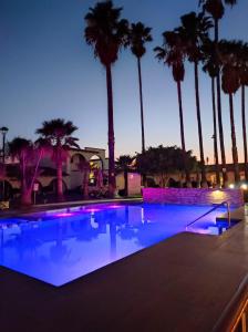 a swimming pool with palm trees at night at Hotel Sand´s San Luis in San Luis Potosí
