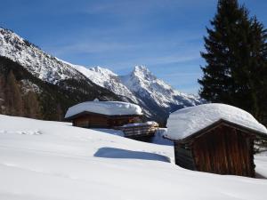 a couple of buildings in the snow with a mountain at Haus Walch in Pettneu am Arlberg
