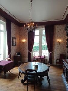 een eetkamer met een tafel en een kroonluchter bij Chateau Maleplane in Saint-Léonard-de-Noblat