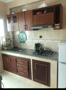 een keuken met houten kasten en een fornuis met oven bij 2 slaapkamers appartement zwembad in Tanger
