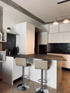 una cucina con armadi bianchi e un bancone con sgabelli di CASA MIA: appartamento con ogni comfort a Rodengo Saiano