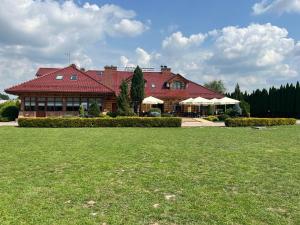 ein großes Haus mit einem Grasfeld davor in der Unterkunft Perła Dunajca Zakliczyn in Zakliczyn