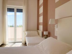 a bedroom with two beds and a large window at Hotel Bencista' in Marina di Pietrasanta