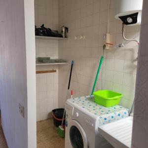 a washing machine with a green bucket on top of it at Apartamento centro de peñíscola CASA KIKO in Peniscola