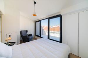a bedroom with a large white bed and a chair at Lusíadas 53 5ºE - Beautiful River View in Lisbon