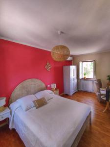 a bedroom with a large bed with a red wall at La Tomatica In Commedia in Mongardino