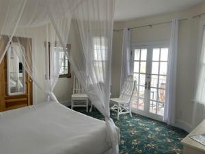 a bedroom with a white bed and a balcony at Hotel Macomber in Cape May