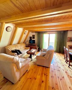 una sala de estar con muebles blancos y techo de madera. en Vikendica Oaza mira, en Žabljak