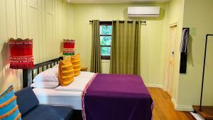 Baan Bua Cottage SHA EXTRA PLUS B5510 في كو كود: غرفة نوم بسرير ومخدات صفراء ونافذة