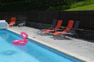 a pink swan in a swimming pool with chairs at The Railway Cottage - characterful and comfortable holiday cottage in Piégut-Pluviers