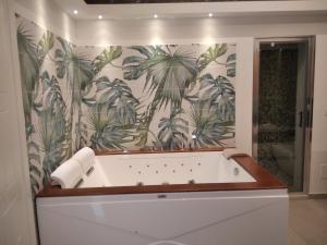 Terra Mia Suite في كاتانيا: حمام مع حوض استحمام مع ورق جدران استوائي