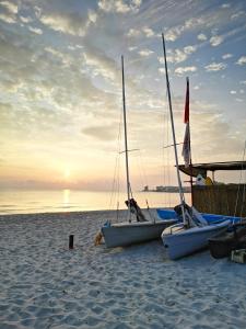 two boats sitting on a beach with the sun setting at Casa Isa al mare in Santa Lucia