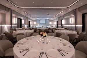 une salle de conférence avec des tables et des chaises blanches dans l'établissement Mii Hotel Srinakarin, à Bangna