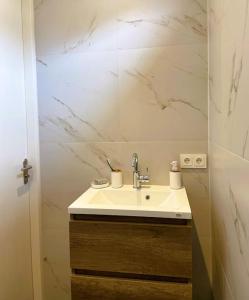 een badkamer met een wastafel en een witte marmeren muur bij Het Zonnetje in Wijk aan Zee