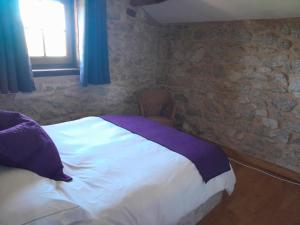 um quarto com uma cama e uma parede de pedra em Character 2 bed cottage within walking distance of bar/restaurants em Piégut-Pluviers