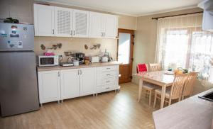 een keuken met witte kasten, een tafel en een koelkast bij Casa Bujor de Munte Dragoslavele in Dragoslavele