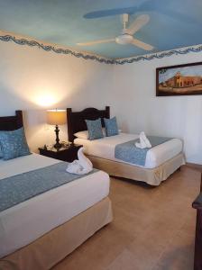 a hotel room with two beds and a ceiling fan at Hotel Zaci in Valladolid