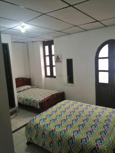 HOTEL LA REPUBLICA MANIZALES في مانيزاليس: غرفة نوم بسريرين ونوافذ