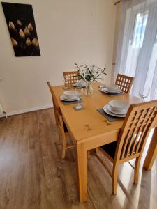 a wooden dining room table with chairs and plates at Contractors Home from Home in South Benfleet
