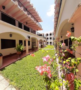 a courtyard of a building with a yard of grass and flowers at Hotel Zaci in Valladolid
