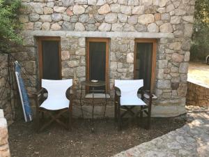 two chairs and a table in front of a stone building at Kyparissi Guest House in Paralía Kiparissi