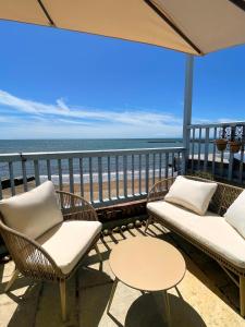 een balkon met stoelen en tafels en de oceaan bij Bell Cliff House in Lyme Regis