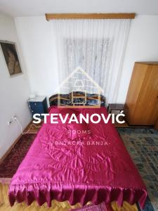 1 dormitorio con cama roja y ventana en Stevanovic Smestaj, en Vrnjci
