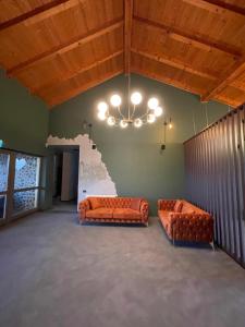 two orange couches in a room with a chandelier at Pensiunea Casa Buna in Gîrbova