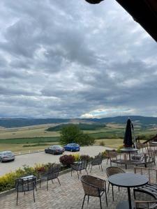 eine Terrasse mit Tischen, Stühlen und Autos in der Ferne in der Unterkunft Pensiunea Casa Buna in Gîrbova