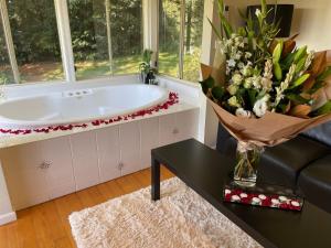 baño con bañera y jarrón de flores en The Mountain View Cottage en The Patch