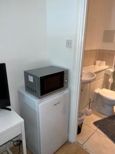 a microwave sitting on top of a refrigerator in a bathroom at The Court in Stone Grove