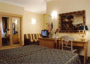 ローマにあるHotel Champagne Palaceのベッド、デスク、テレビが備わるホテルルームです。