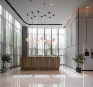 a lobby with a reception desk and large windows at Mii Hotel Srinakarin in Bangna