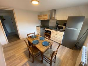 a kitchen with a wooden table with chairs and a refrigerator at Logement Pays des Écrins in La Roche-de-Rame