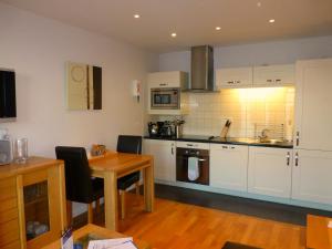 a kitchen with white cabinets and a wooden table at Liberty Wharf Apartments in Saint Helier Jersey