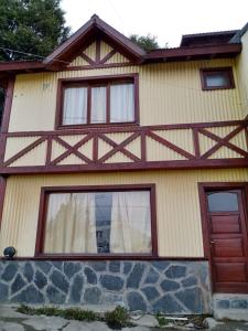 ein Haus mit einem Holzzaun darauf in der Unterkunft Calida cabaña in Ushuaia