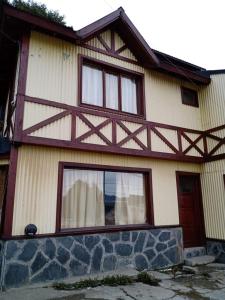 a house with three windows and a stone wall at Calida cabaña in Ushuaia