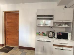 a kitchen with white cabinets and a door at Las Dalias in Cusco