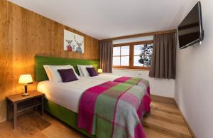 a bedroom with a large bed and a television at ARLhome Lodge - Zuhause am Arlberg in Sankt Anton am Arlberg