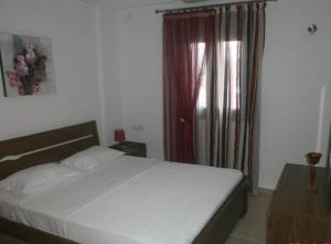 a bedroom with a white bed and a window at Kyparissi in Kamilari