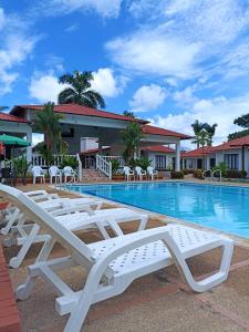 a row of white lounge chairs next to a swimming pool at Cabañas LLano Lindo Apiay in Villavicencio