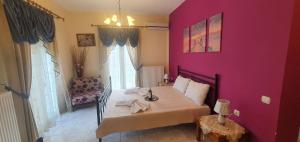 1 dormitorio con pared de color rosa, cama y silla en panos rooms, en Kalambaka