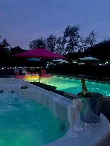 a swimming pool at night with a drink in a bucket at The Farm Exclusive Hire in Stapleford Tawney