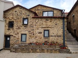 Una casa de piedra con un cartel en el costado. en Casa do Pátio e Casa da Serra en Castanheira de Pêra