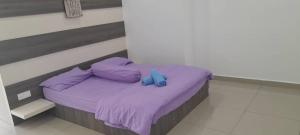 een bed met paarse lakens en een blauw voorwerp erop bij Idaman Homestay in Kampong Lumut Kiri