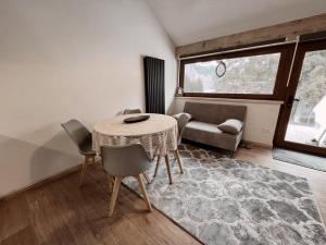 sala de estar con mesa, sillas y sofá en Loft Malga Laghetto en Lavarone