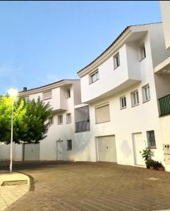 un grand bâtiment blanc avec deux portes de garage dans l'établissement Agradable Adosado 3 plantas Altea, à Altea