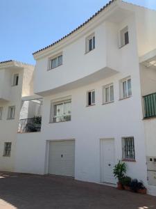 - un immeuble blanc avec deux portes de garage dans l'établissement Agradable Adosado 3 plantas Altea, à Altea