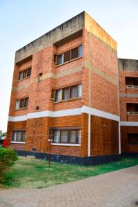 um edifício de tijolos vermelhos com janelas do lado em Specious Old Zamtel flats em Lusaka