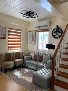ein Wohnzimmer mit einem Sofa und einer Treppe in der Unterkunft Delightful House in the Heart of Legazpi, Albay. in Legazpi